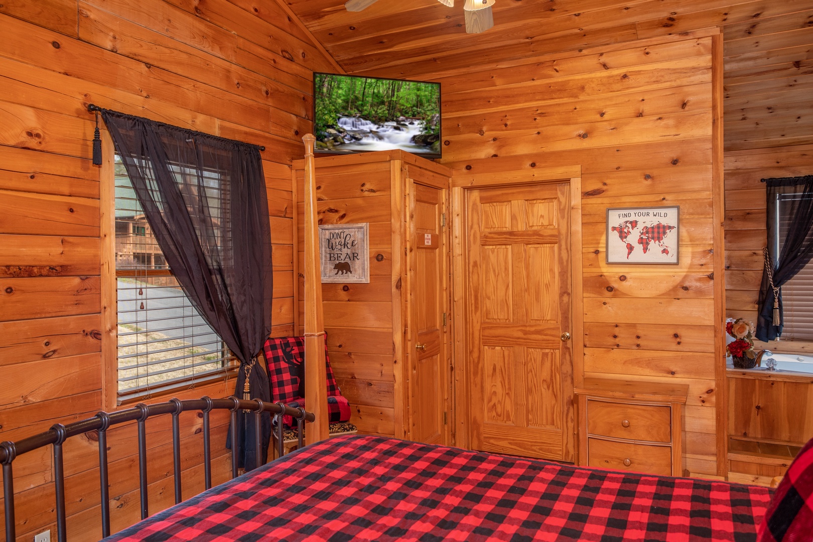 Bedroom with a television and in-room jacuzzi at Hibernation Station, a 3-bedroom cabin rental located in Pigeon Forge