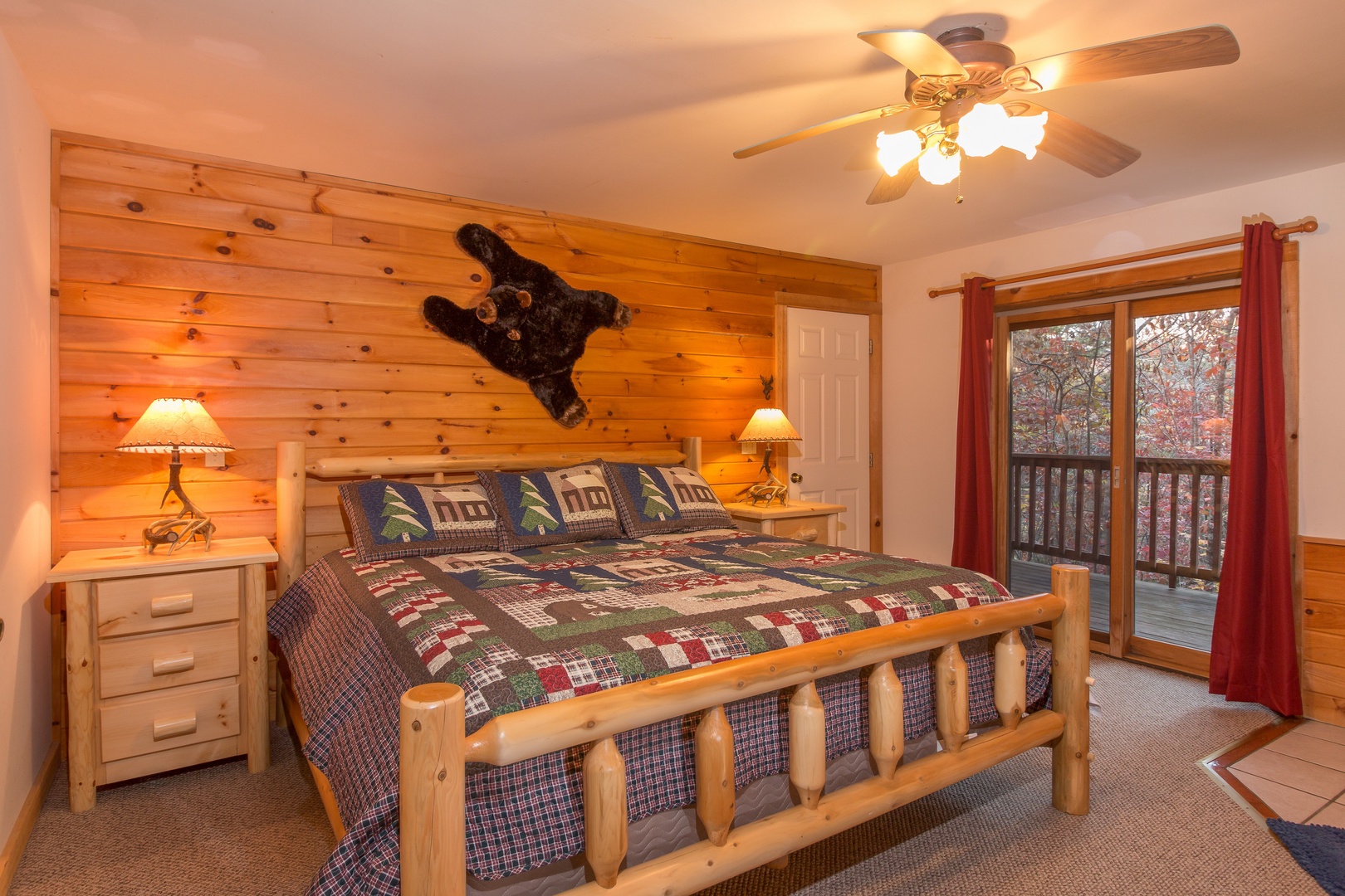 Bedroom with a log bed, night stands, lamps, and deck access at Just for Fun, a 4 bedroom cabin rental located in Pigeon Forge