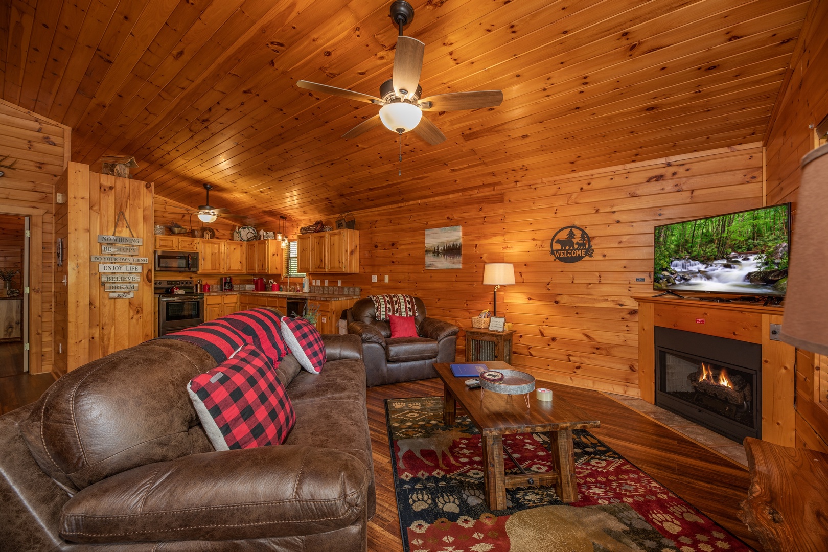 Living room with fireplace and TV next to the open kitchen at Hawk's Heart Lodge, a 3 bedroom cabin rental located in Pigeon Forge
