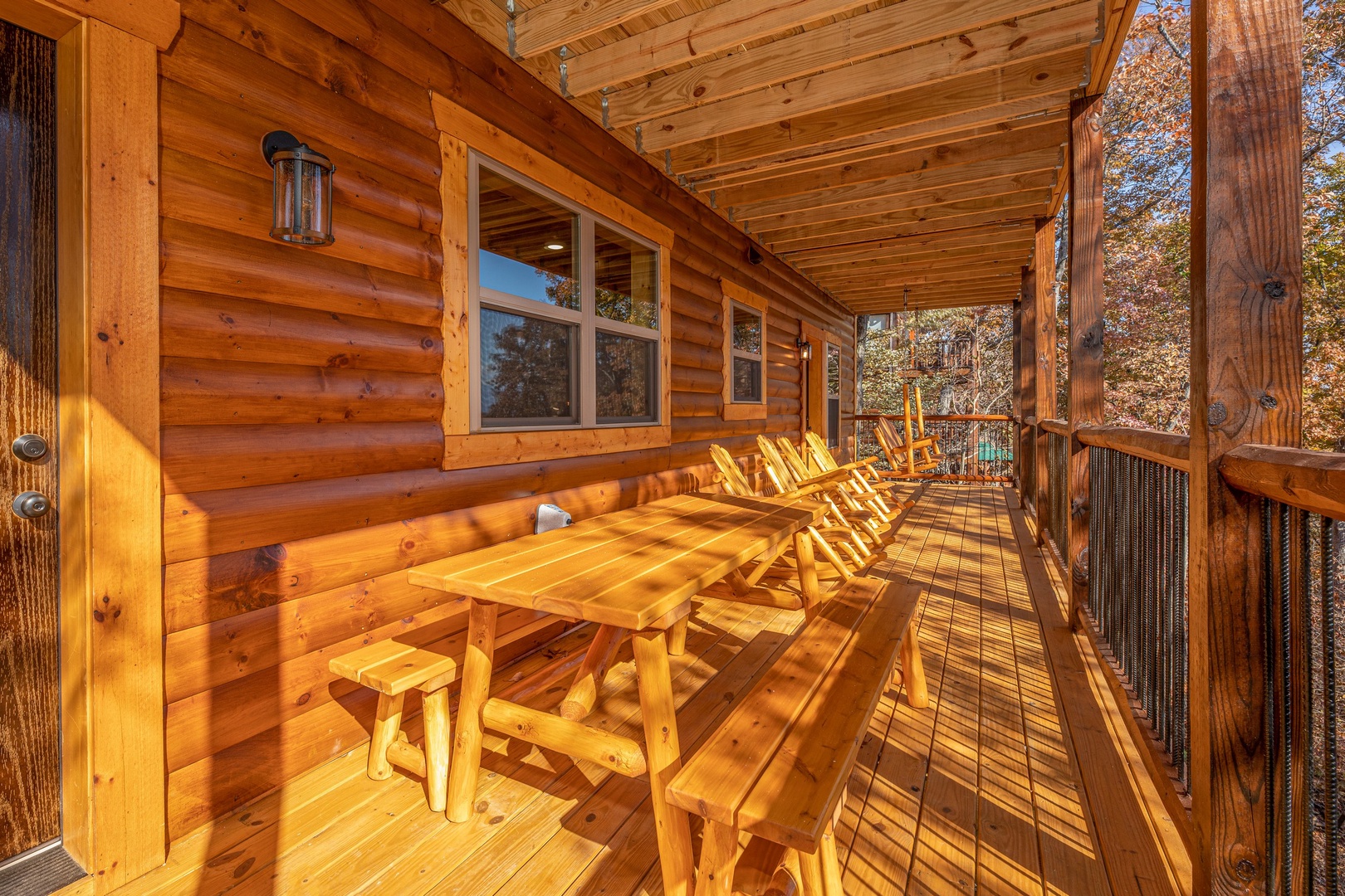 Picnic table and rocking chairs on a covered deck at Pinot Splash, a 4 bedroom cabin rental located in Gatlinburg