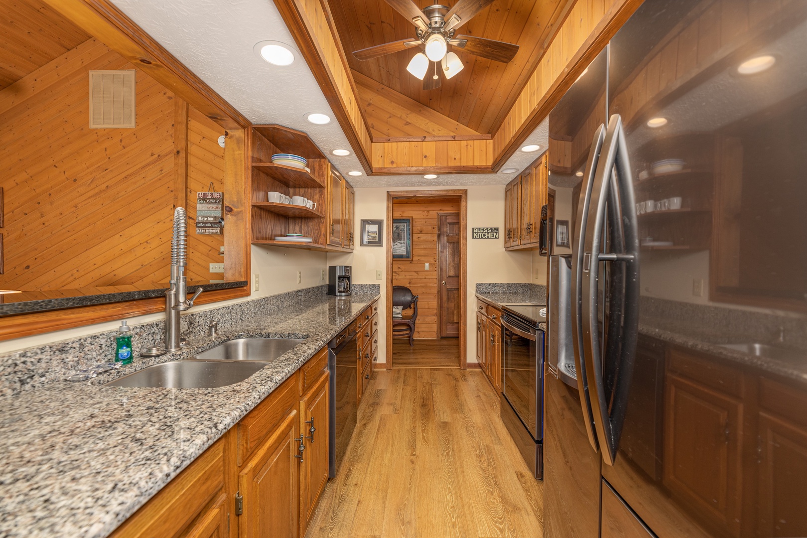 Galley kitchen with granite counters and black appliances at Cubs' Crib, a 3 bedroom cabin rental located in Gatlinburg