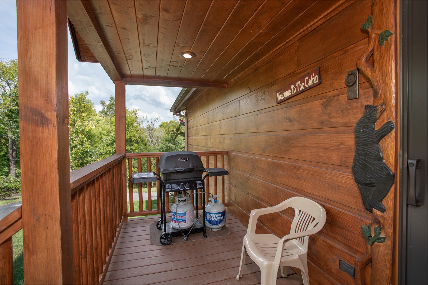 Propane grill on a covered deck with custom black bear decor at Cedar Creeks, a 2-bedroom cabin rental located near Douglas Lake