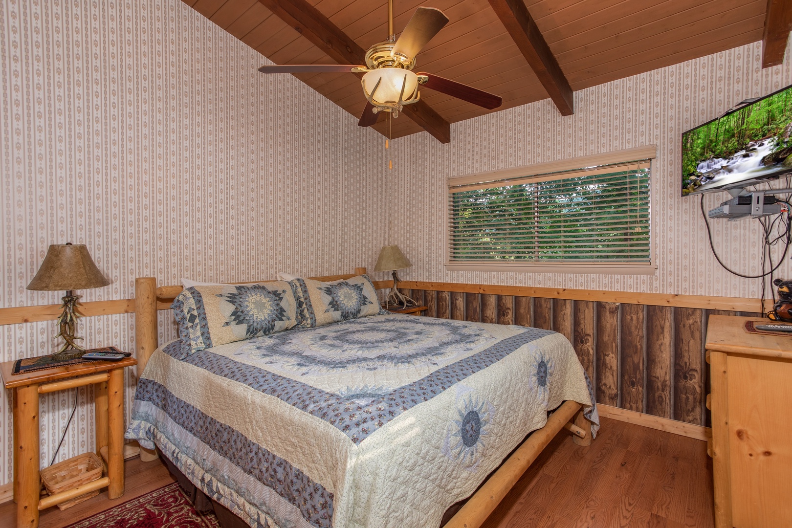King-sized log bed in a bedroom with a TV and dresser at Bushwood Lodge, a 3-bedroom cabin rental located in Gatlinburg