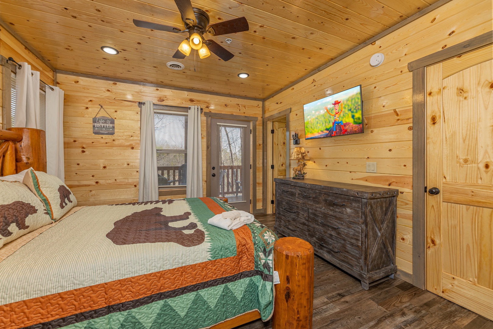 Dresser, second TV, and deck access in a bedroom at Everly's Splash, a 4 bedroom cabin rental located in Pigeon Forge