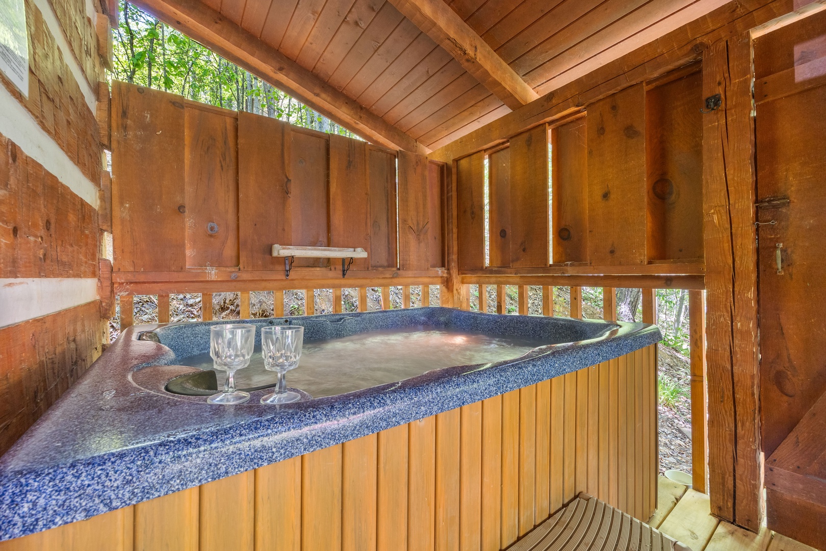 Hot tub on a covered deck with privacy fence at Bearfoot Crossing, a 1-bedroom cabin rental located in Pigeon Forge