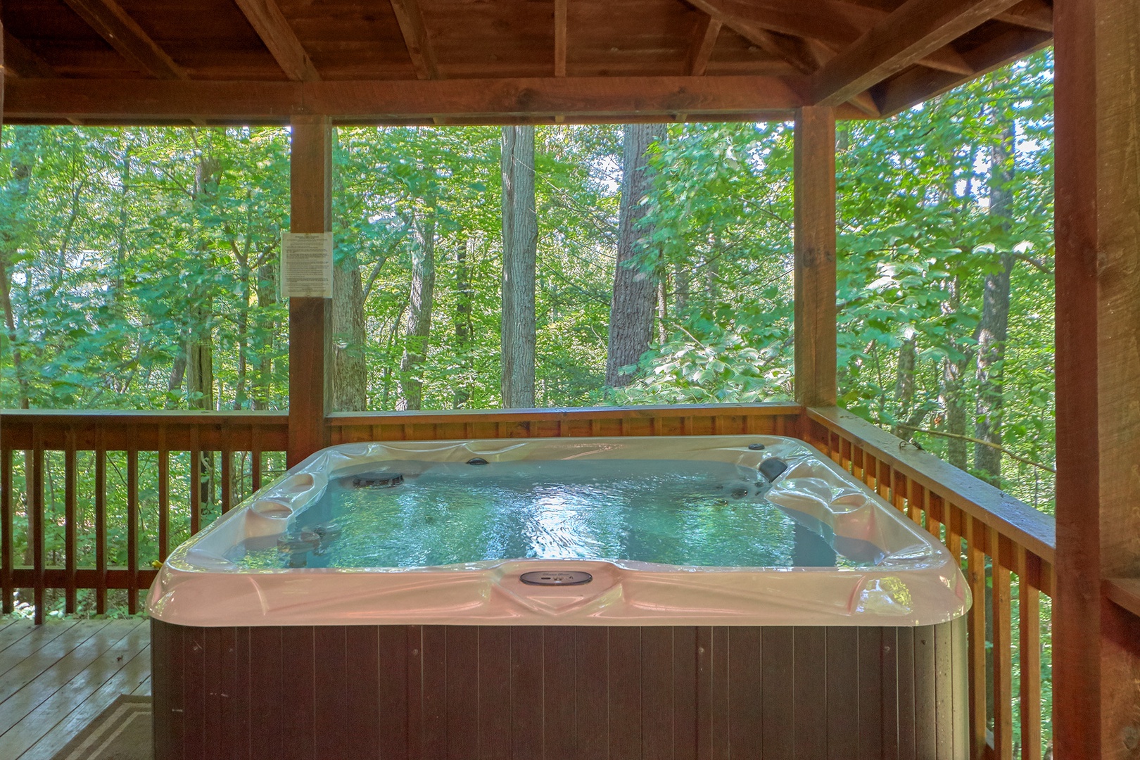 Hot tub on a covered deck with a woods view at A Place to Remember, a 2 bedroom cabin rental located in Gatlinburg