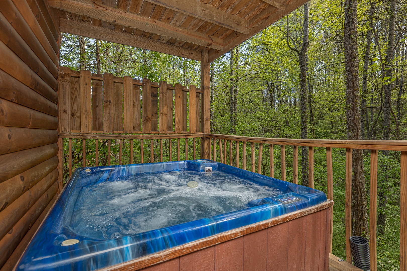 Hot tub on a covered deck with privacy fence at A Moment in Time, a 2 bedroom cabin rental located in Pigeon Forge