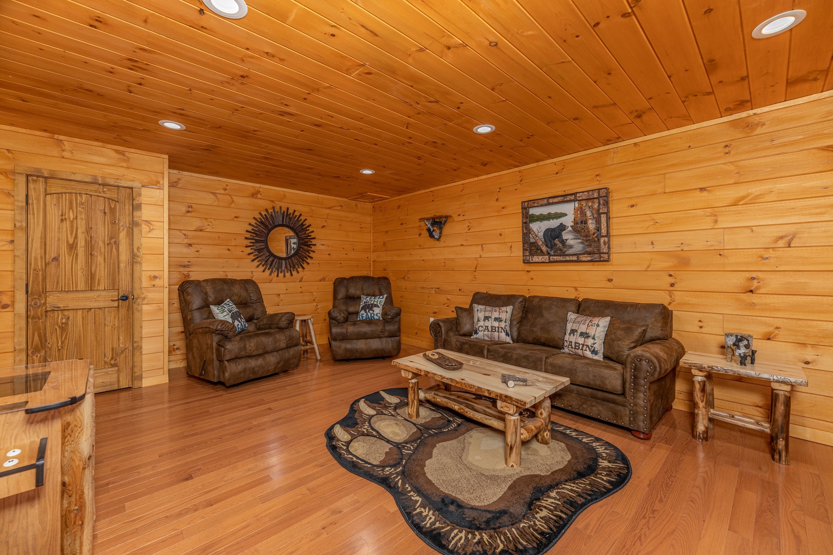 Sofa, two recliners, and video game in the lower living room at J's Hideaway, a 4 bedroom cabin rental located in Pigeon Forge