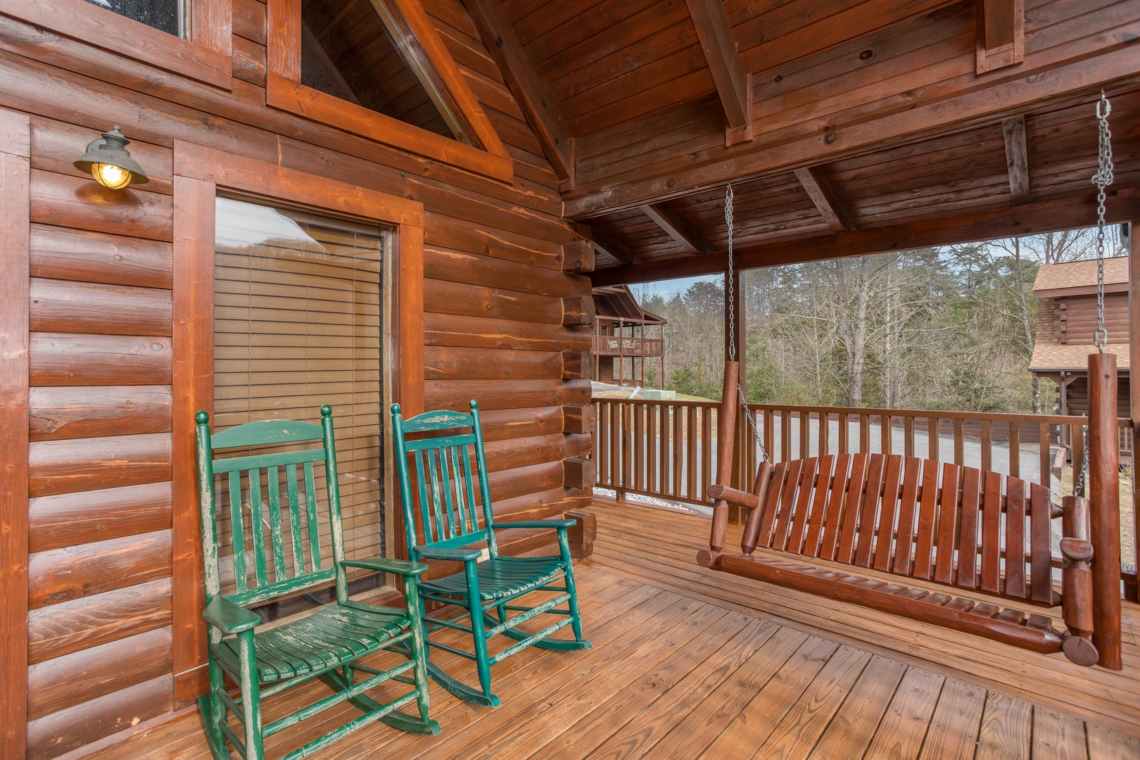 Swing and rocking chairs on the covered deck at Hibernation Station, a 3-bedroom cabin rental located in Pigeon Forge