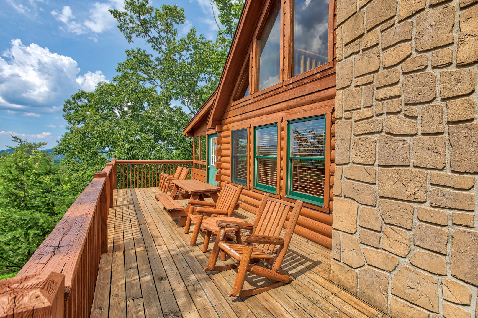 Adirondack chairs, picnic table, and rocking chairs on the deck at Cabin in the Clouds, a 3-bedroom cabin rental located in Pigeon Forge