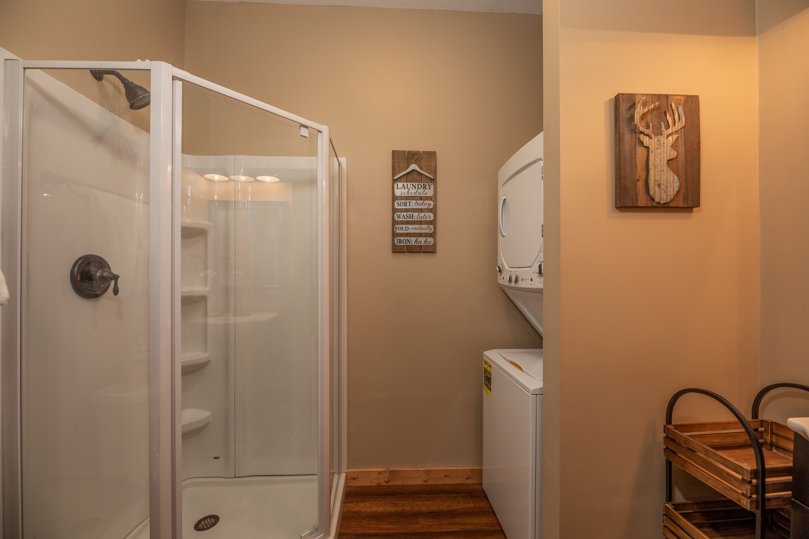 Stacked washer and dryer next to a shower stall in a bathroom at Hawk's Heart Lodge, a 3 bedroom cabin rental located in Pigeon Forge
