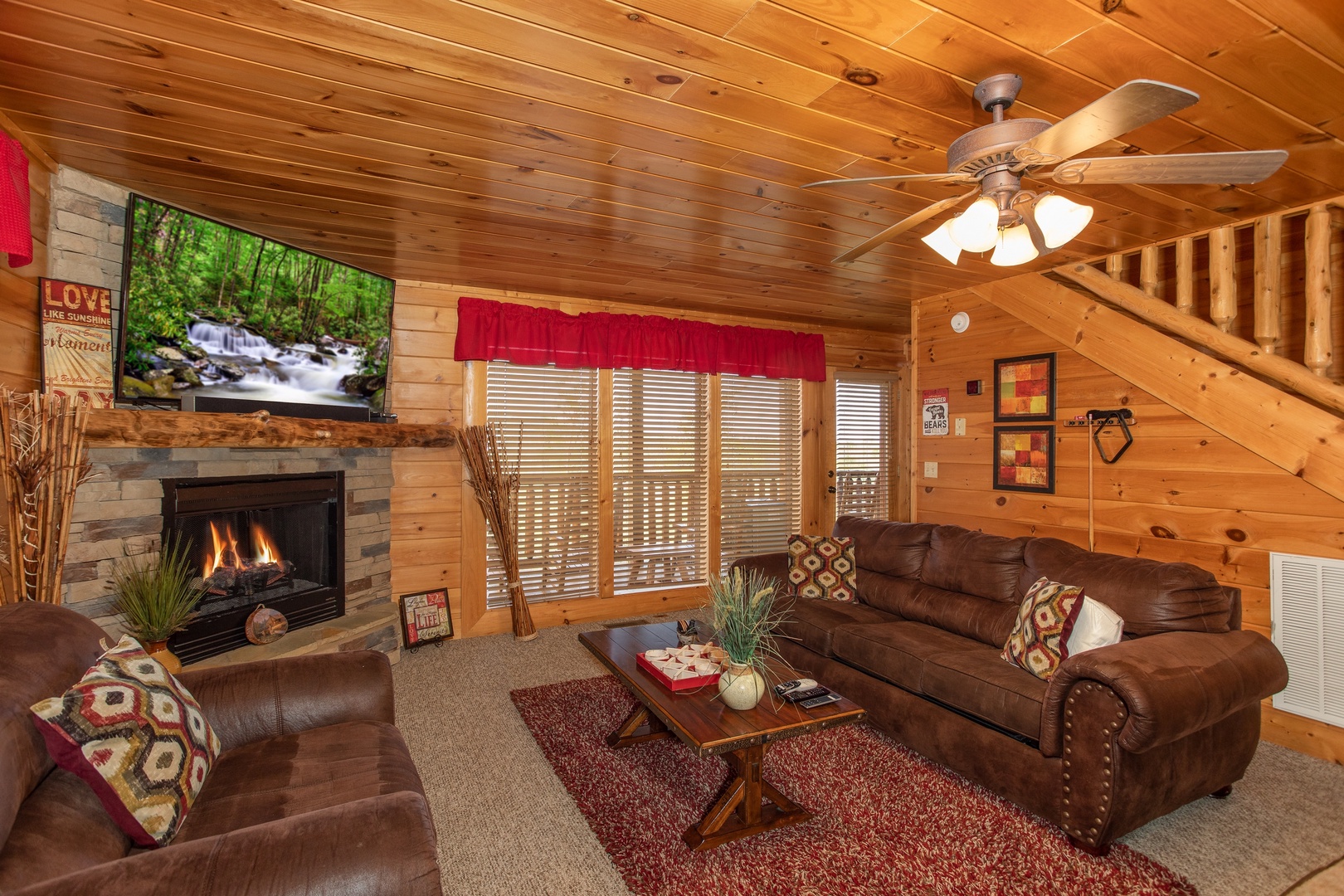 Sofa, fireplace, TV, and deck access from the family room at Better View, a 4 bedroom cabin rental located in Pigeon Forge
