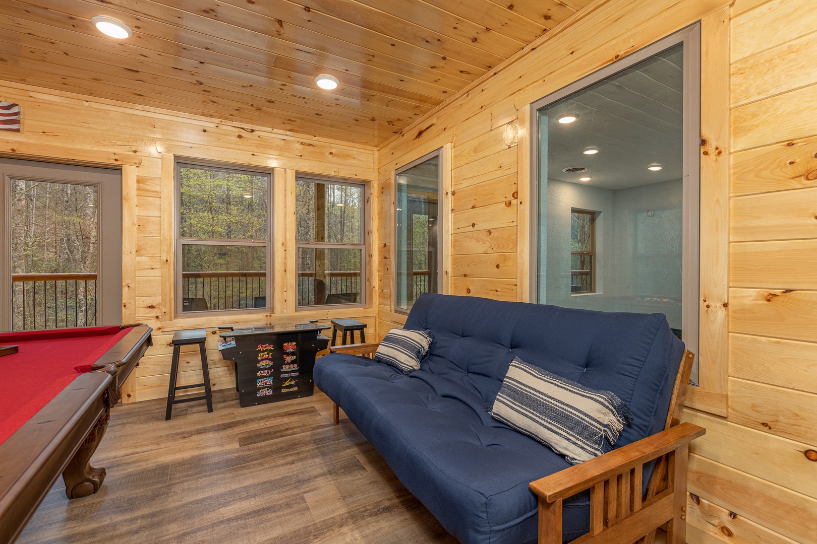 Futon and arcade game at Poolin Around, a 2 bedroom cabin rental located in Gatlinburg