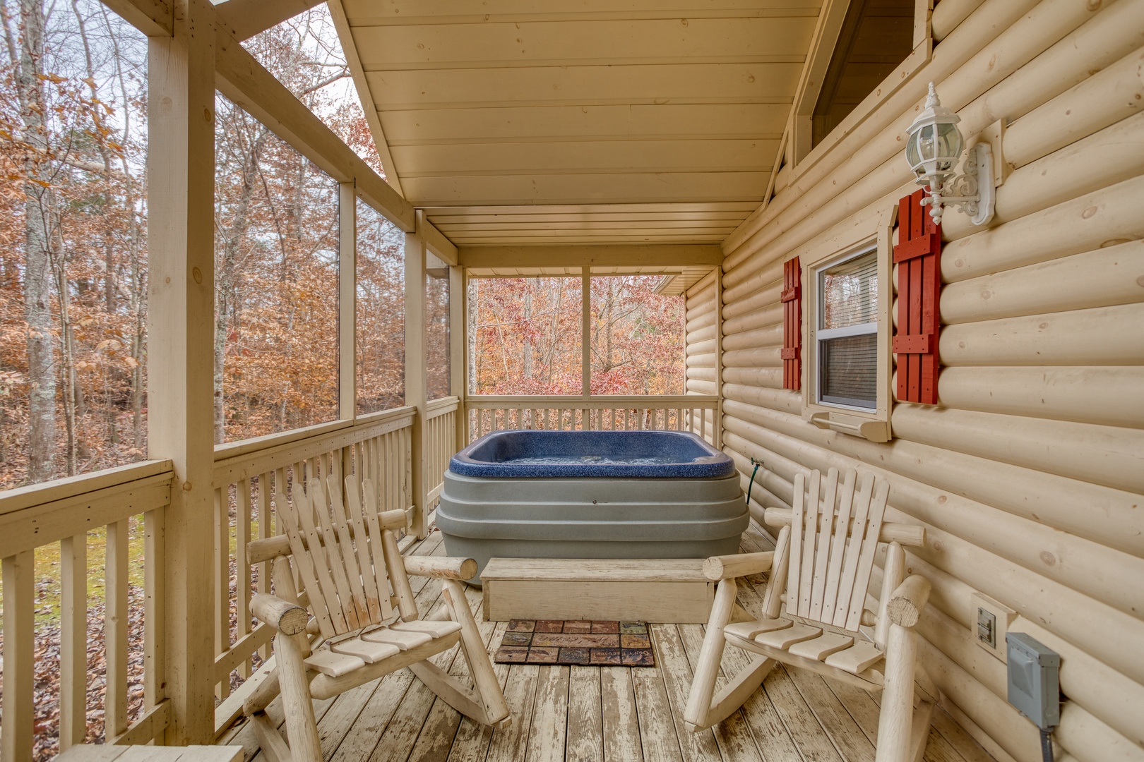 Hot tub on a screened in, covered porch with two log rockers at Bearly in the Mountains, a 5-bedroom cabin rental located in Pigeon Forge