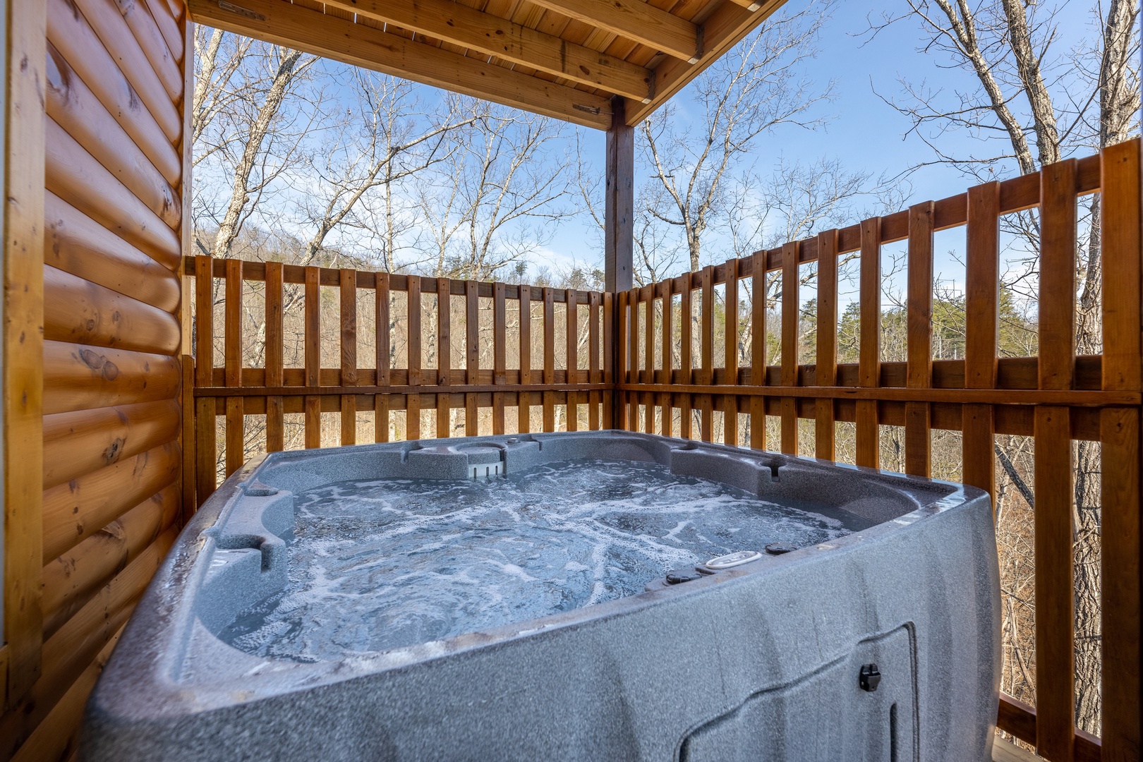 Hot tub on a covered deck at Everly's Splash, a 4 bedroom cabin rental located in Pigeon Forge