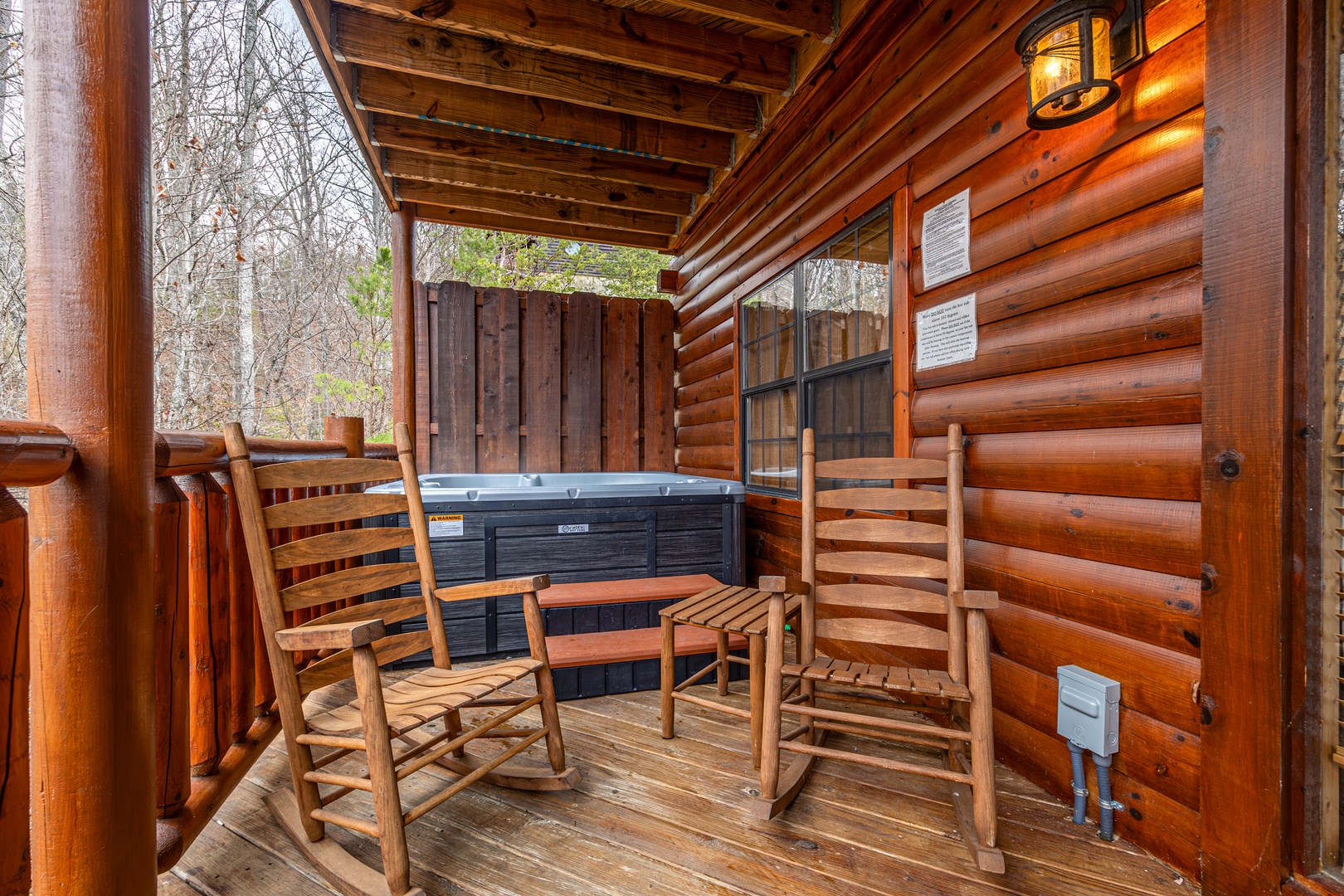 Covered porch with rocking chairs and a hot tub at Family Ties Lodge