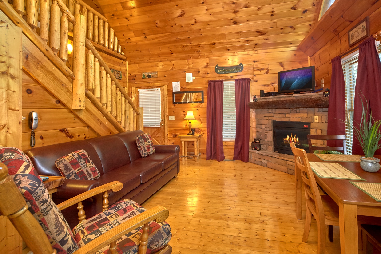 Living room with fireplace, TV, and dining space at Love Struck, a 1 bedroom cabin rental located in Pigeon Forge