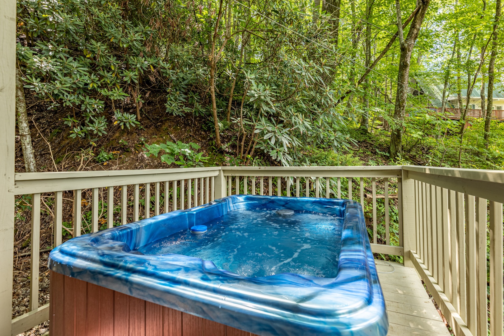 Hot tub on a deck surrounded by trees at License to Chill, a 3 bedroom cabin rental located in Gatlinburg