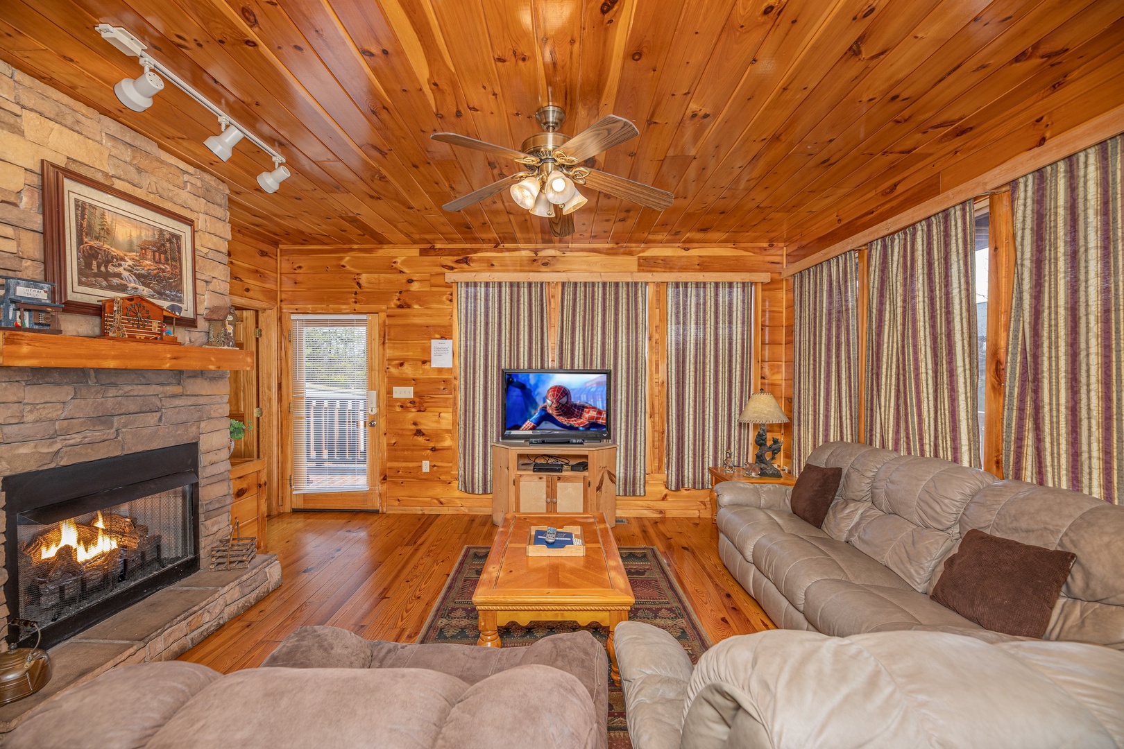Main living room with TV, fireplace, and seating at Hickernut Lodge, a 5-bedroom cabin rental located in Pigeon Forge