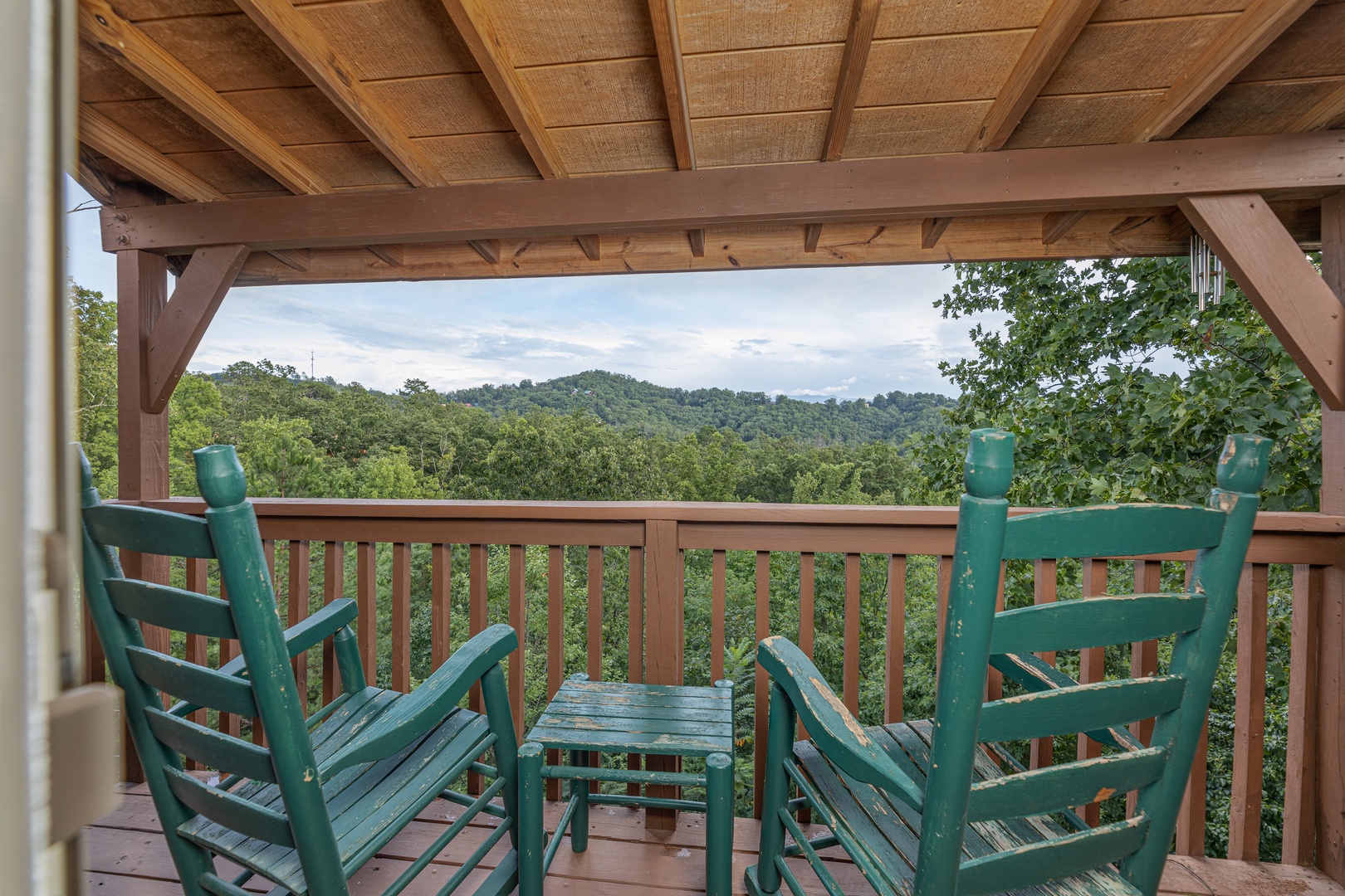 Green rocking chairs on a covered deck at Bearing Views, a 3 bedroom cabin rental located in Pigeon Forge