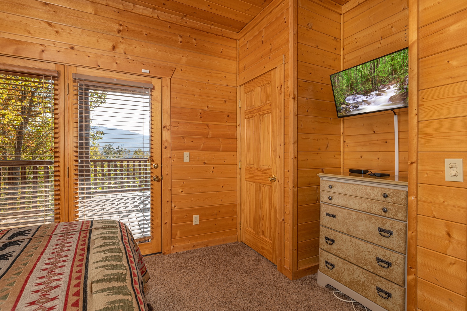 Dresser, TV, and deck access in a bedroom at Grizzly's Den, a 5 bedroom cabin rental located in Gatlinburg