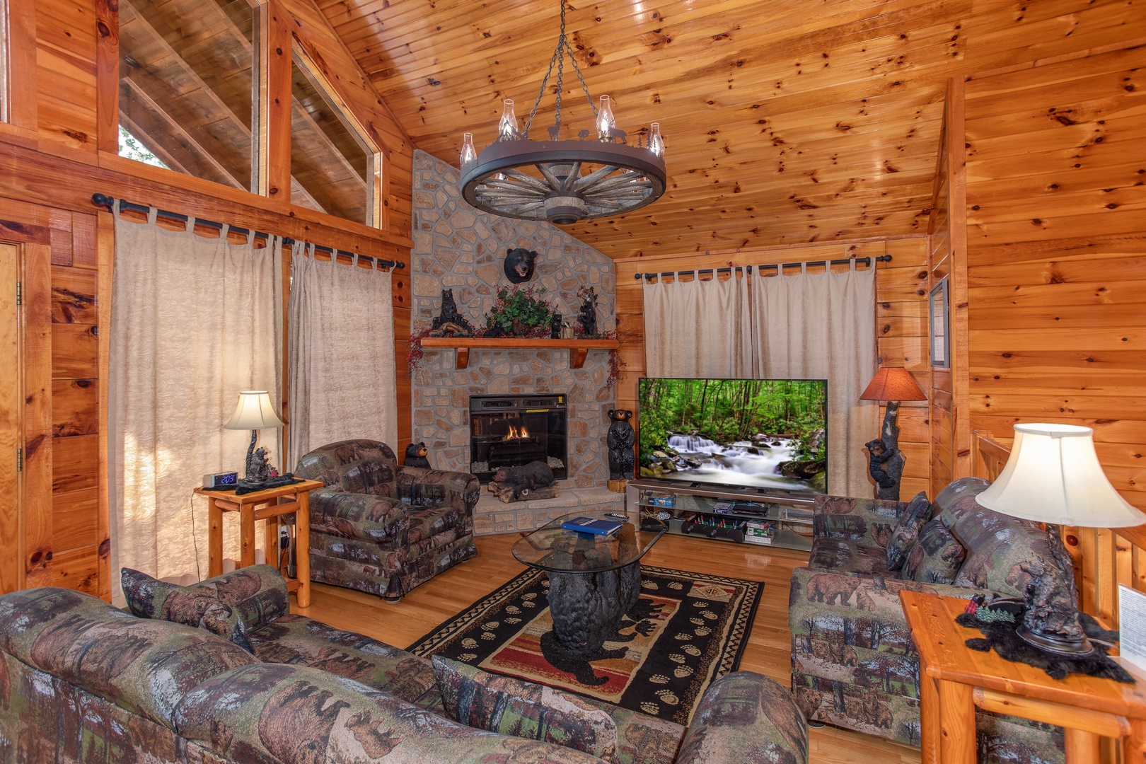 Living room with corner stone fireplace and wagon wheel chandelier at Bear Country, a 3-bedroom cabin rental located in Pigeon Forge