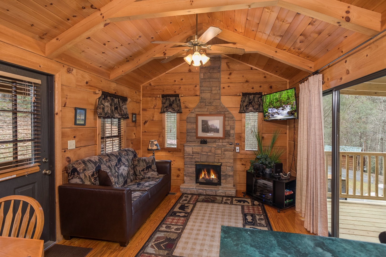 Stone fireplace, TV, and sofa in the living room at Boogie Bear, a 1-bedroom cabin rental located in Gatlinburg