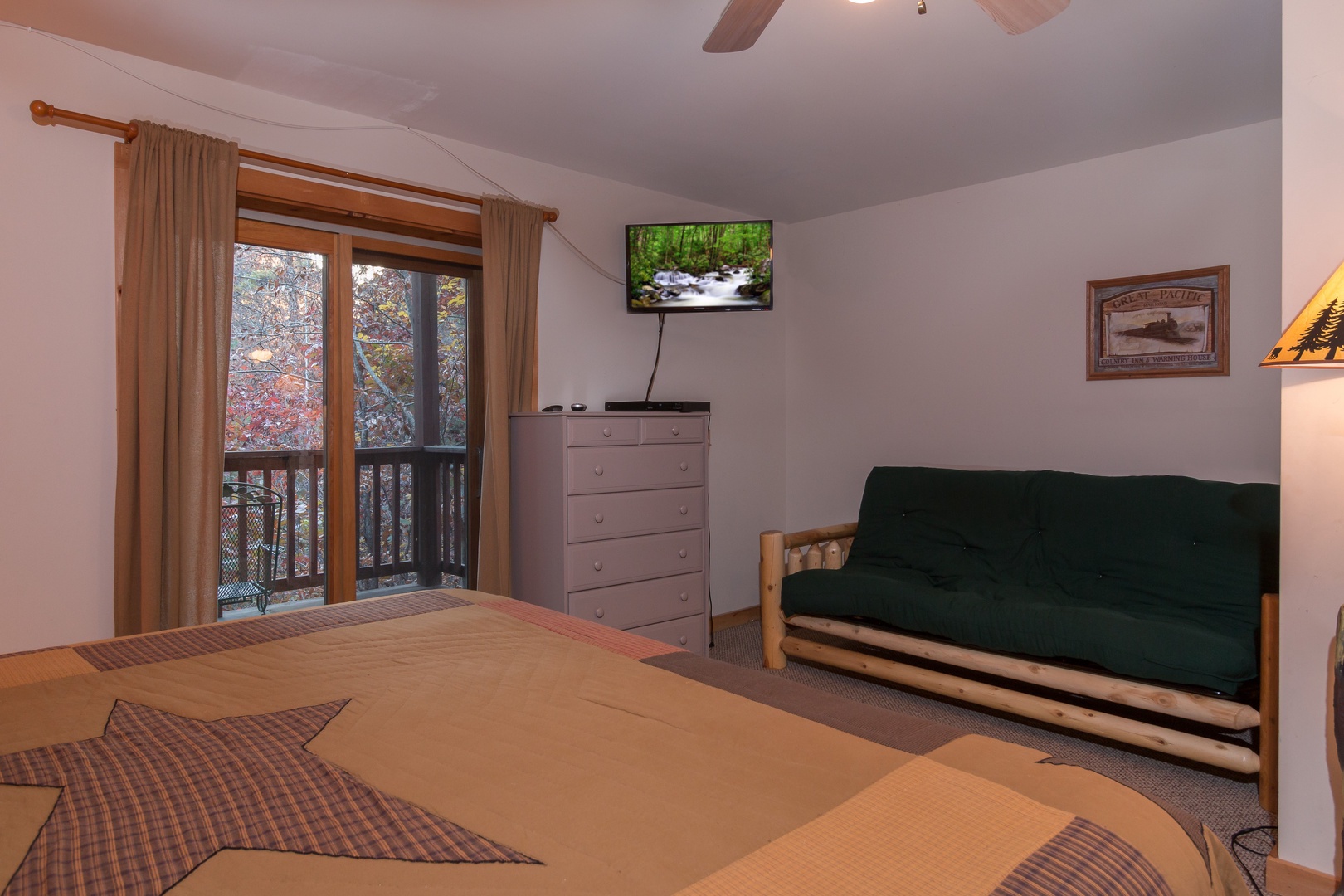 Futon, dresser, TV, and deck access in a bedroom at Just for Fun, a 4 bedroom cabin rental located in Pigeon Forge