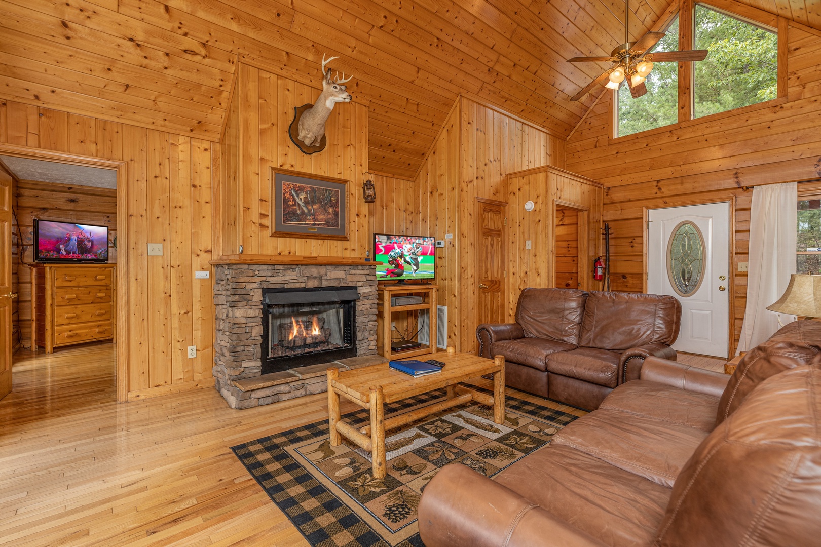 Sofa, loveseat, fireplace, and TV in a living room at Wildlife Retreat, a 3 bedroom cabin rental located in Pigeon Forge