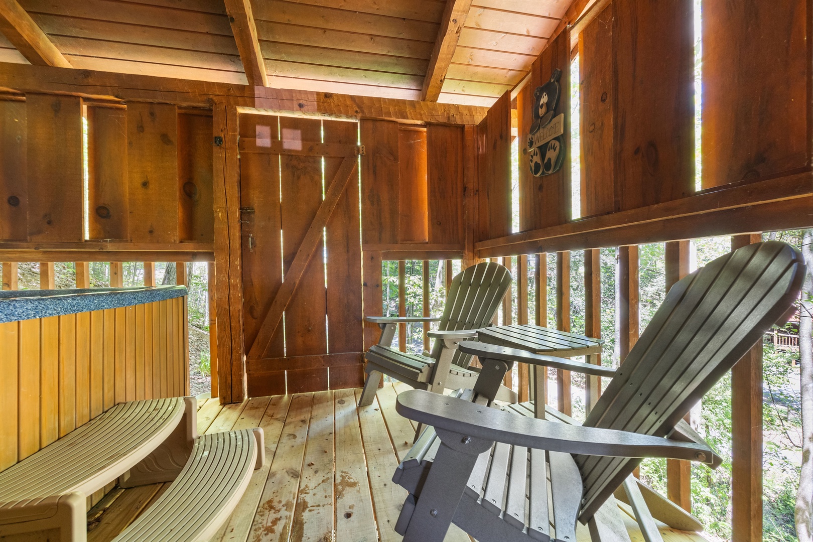 Seating on a covered deck with privacy fence at Bearfoot Crossing, a 1-bedroom cabin rental located in Pigeon Forge