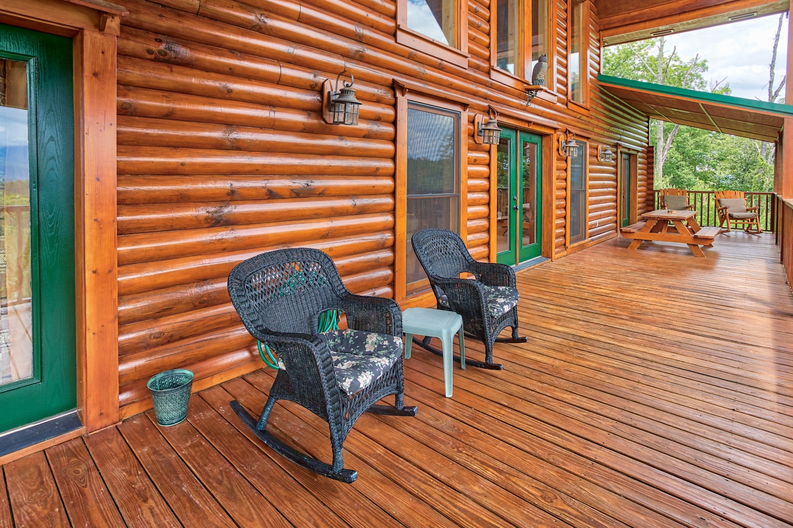 Wicker rocking chairs on the covered deck at I Do Love Views, a 3 bedroom cabin rental located in Pigeon Forge