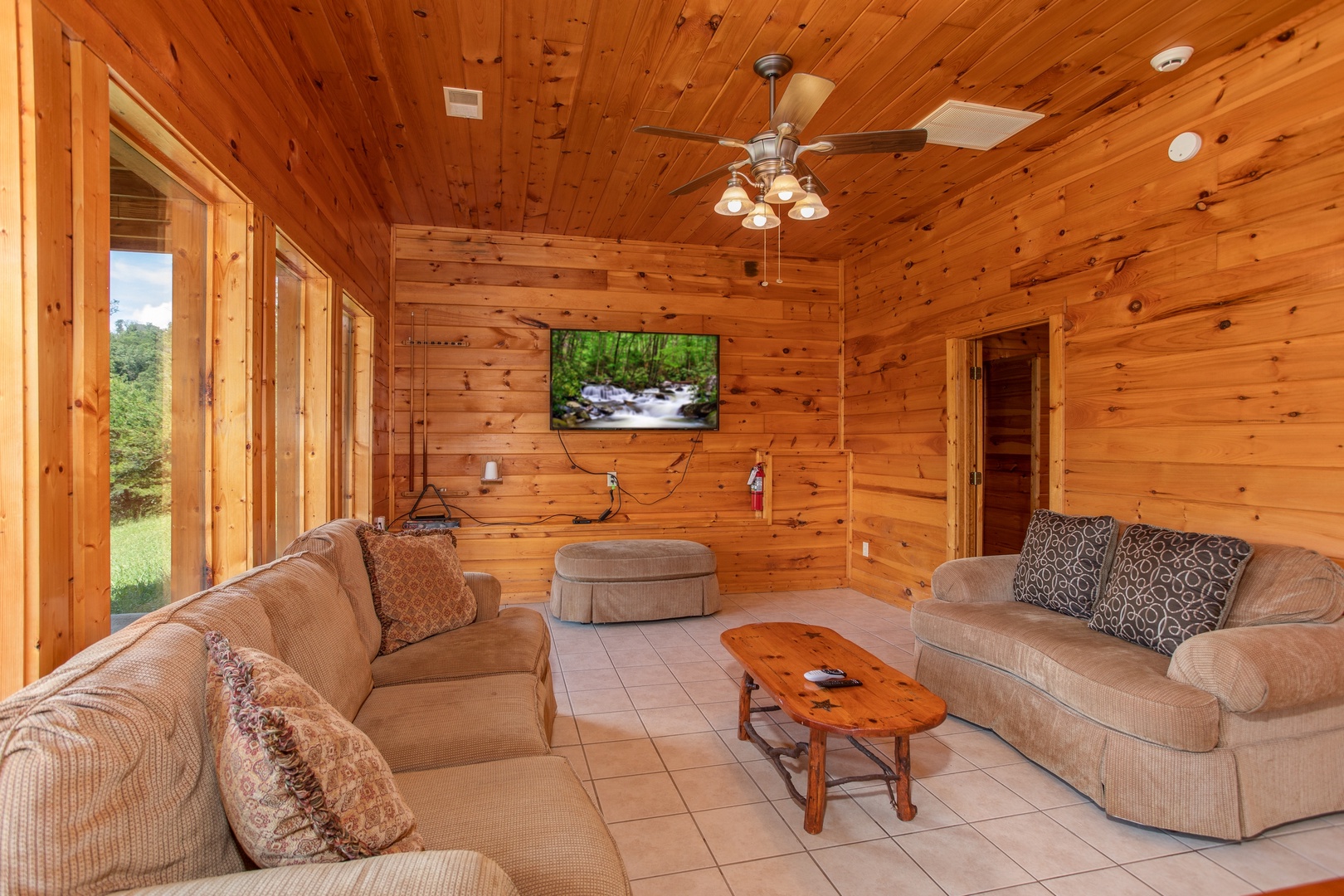 Television, couch, loveseat, and ottoman in the game room at Cabin Fever, a 4-bedroom cabin rental located in Pigeon Forge