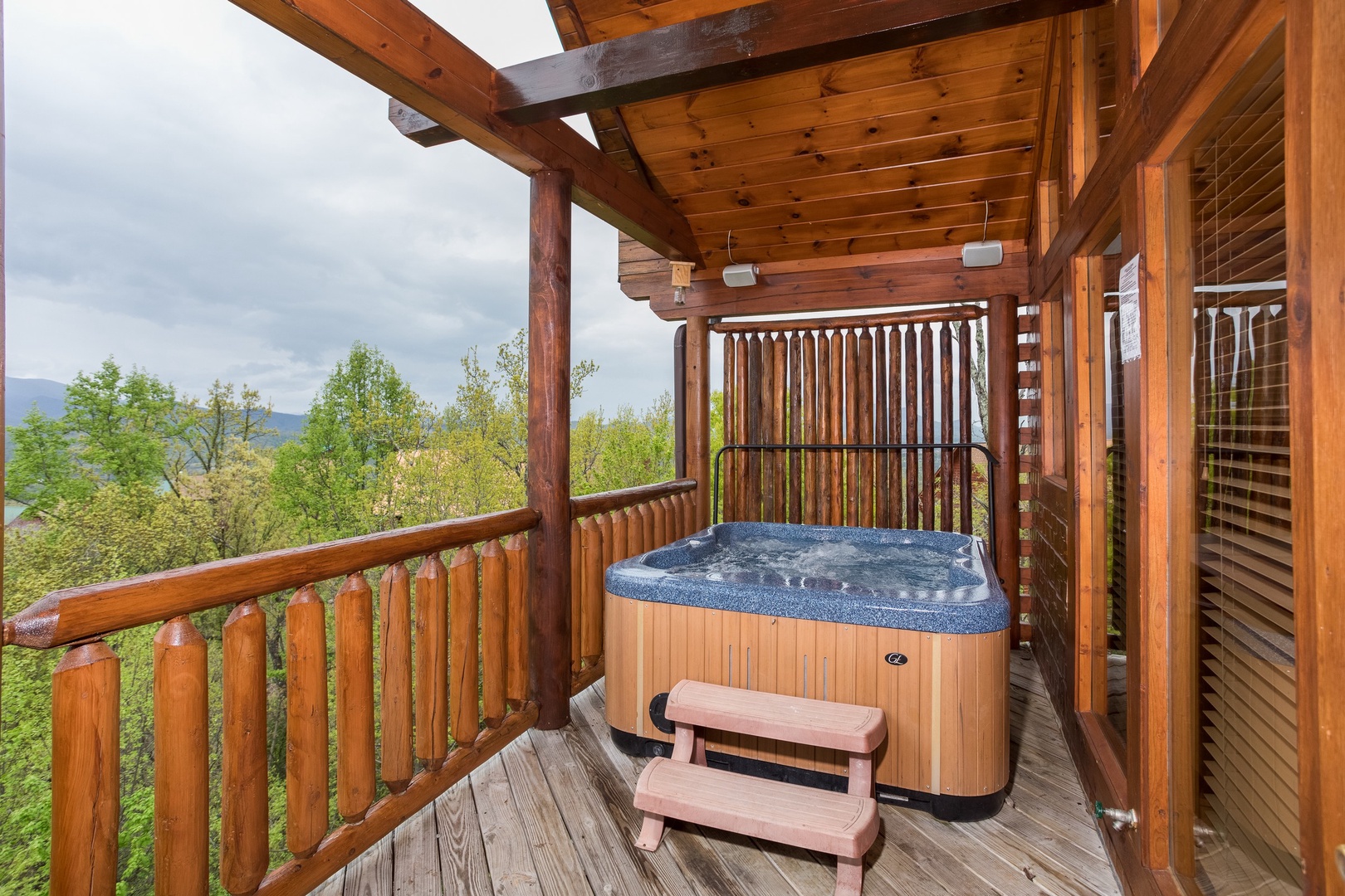 Hot tub on a covered deck at Howlin' in the Smokies, a 2 bedroom cabin rental located in Pigeon Forge