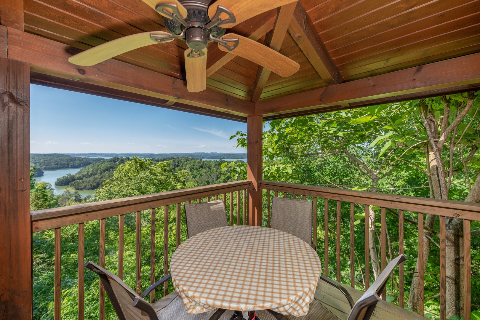Table for four on a covered deck with a fan and a lake view at Grand View, a 3 bedroom cabin rental located in Sevierville