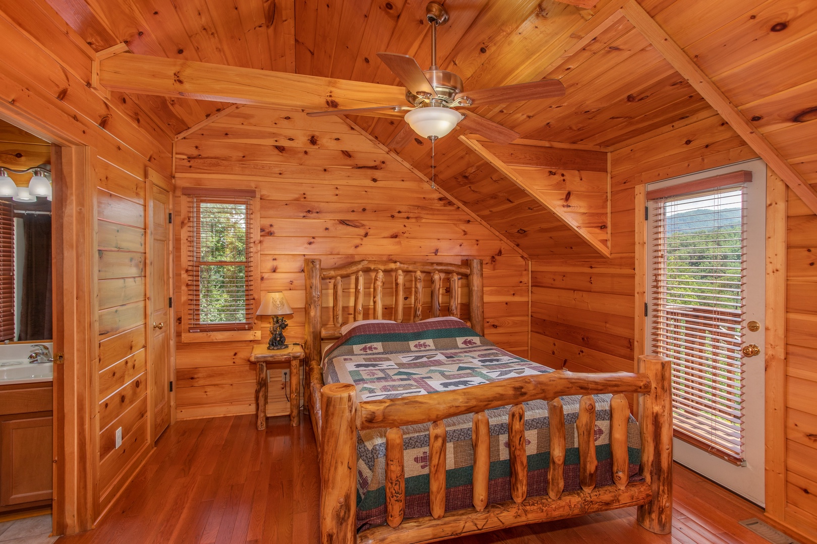 Queen-sized log bed in a bedroom with deck access at Four Seasons Lodge, a 3-bedroom cabin rental located in Pigeon Forge