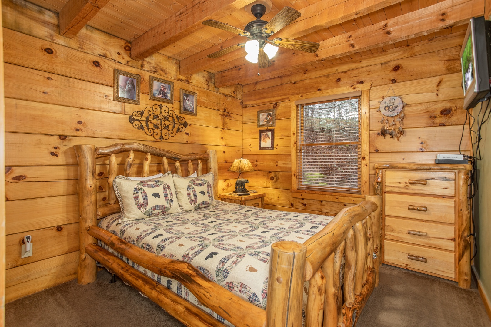 Bedroom with a queen sized log bed, dresser, and TV at Alpine Romance, a 2 bedroom cabin rental located in Pigeon Forge