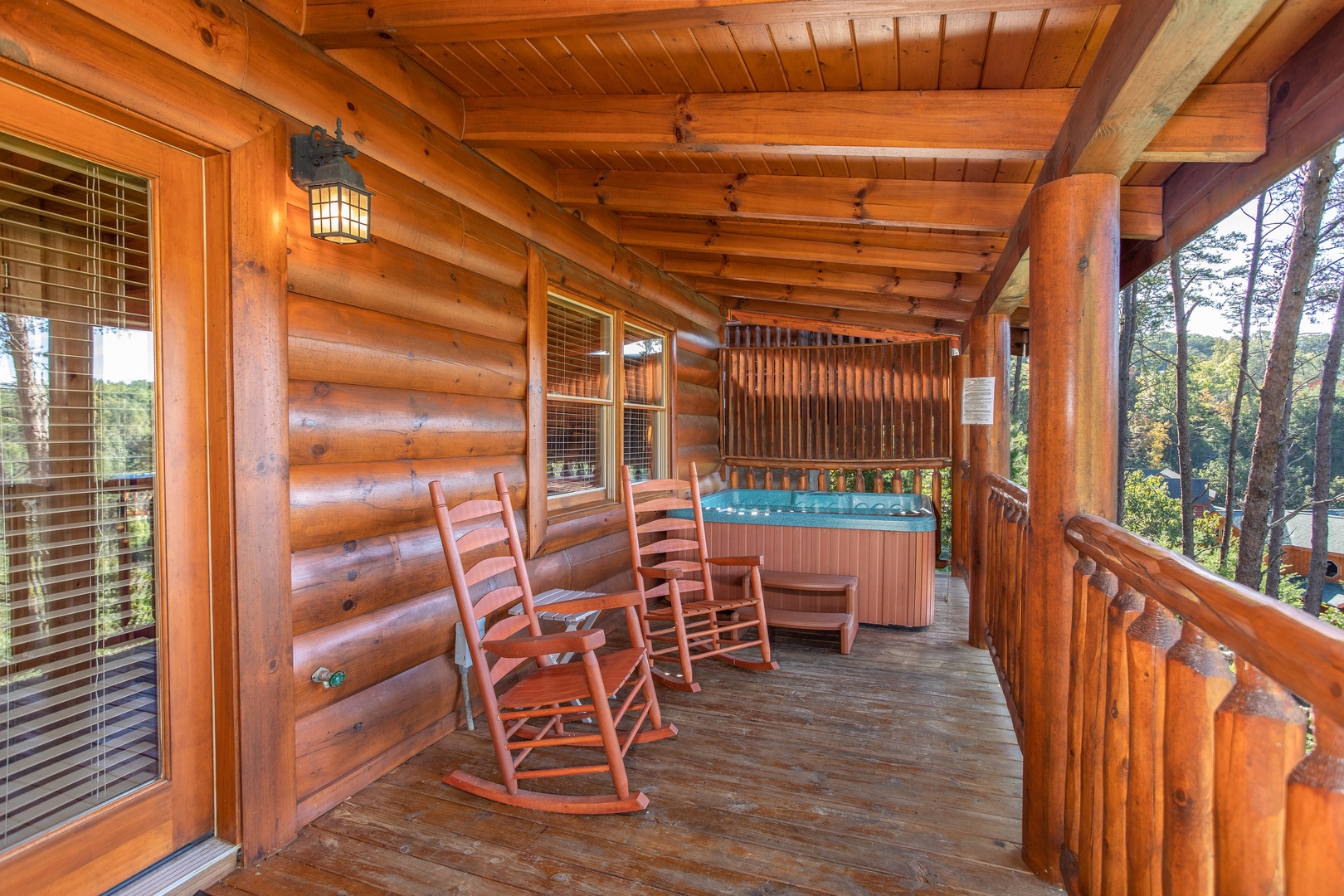 Rocking chairs and hot tub with a privacy fence on a covered deck at Bears Eye View, a 2-bedroom cabin rental located in Pigeon Forge