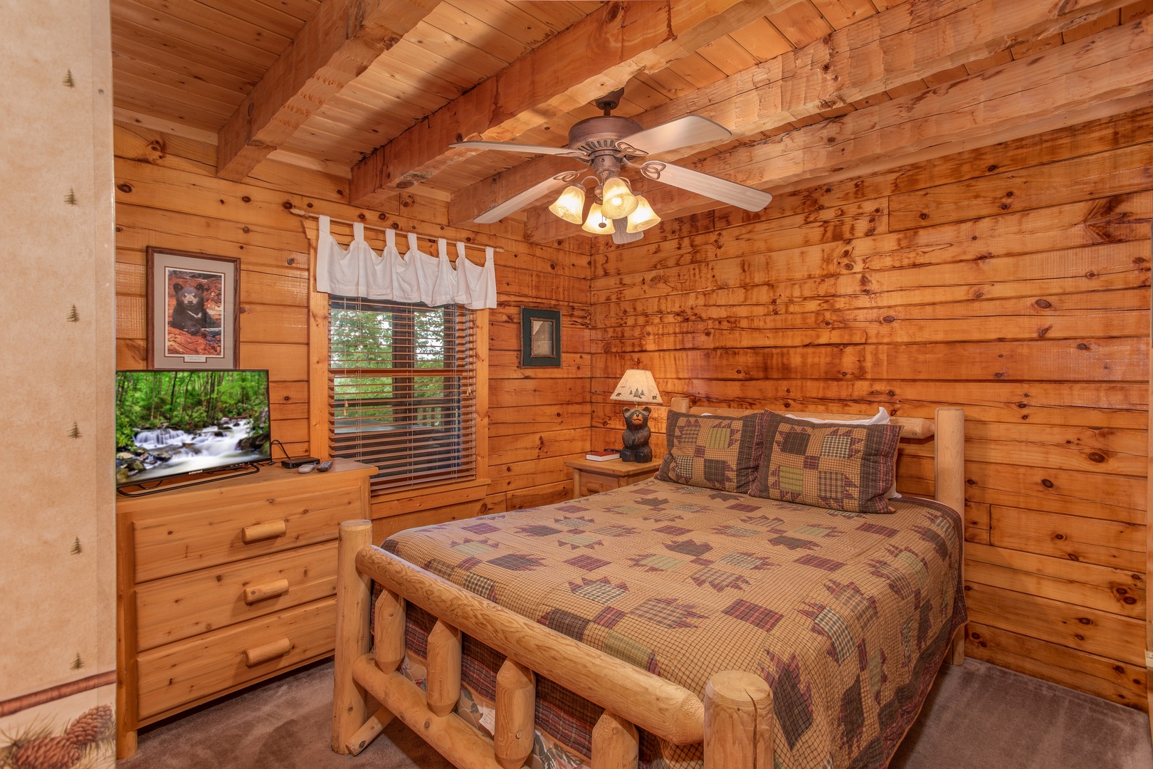 Log bed, dresser, and a television in a bedroom at Cabin in the Clouds, a 3-bedroom cabin rental located in Pigeon Forge