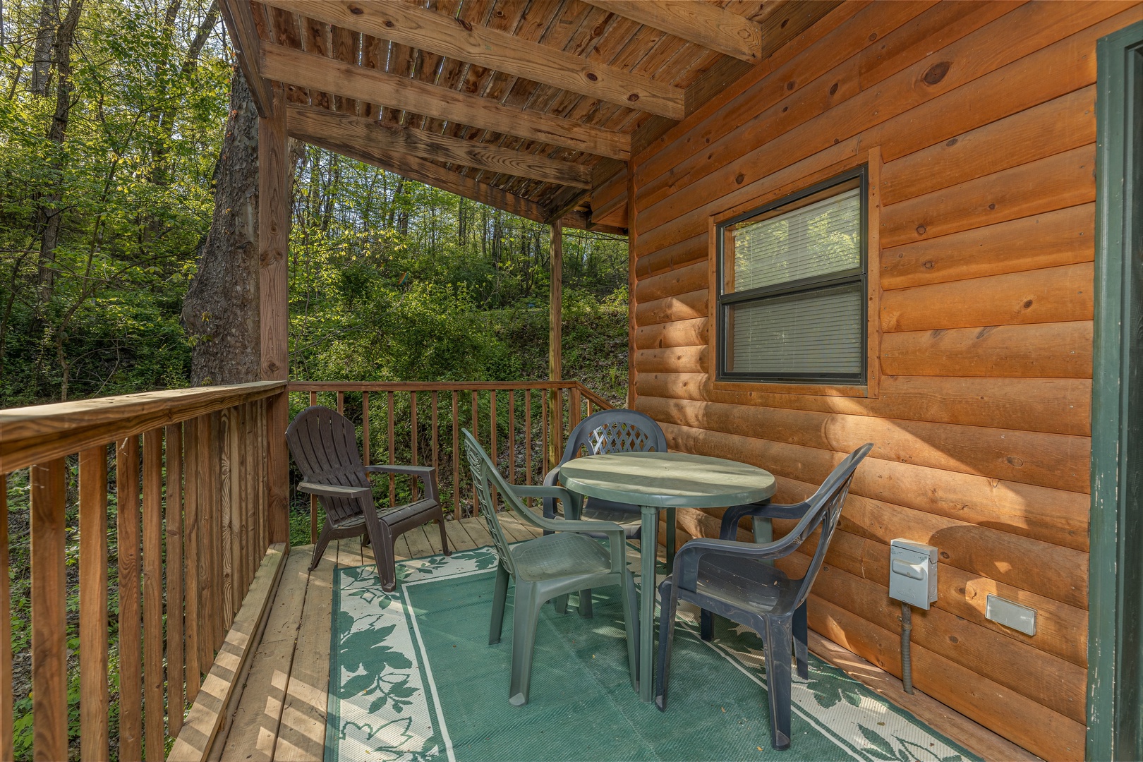 Dining table with three chairs on a covered deck at A Cheerful Heart, a 2 bedroom cabin rental located in Pigeon Forge