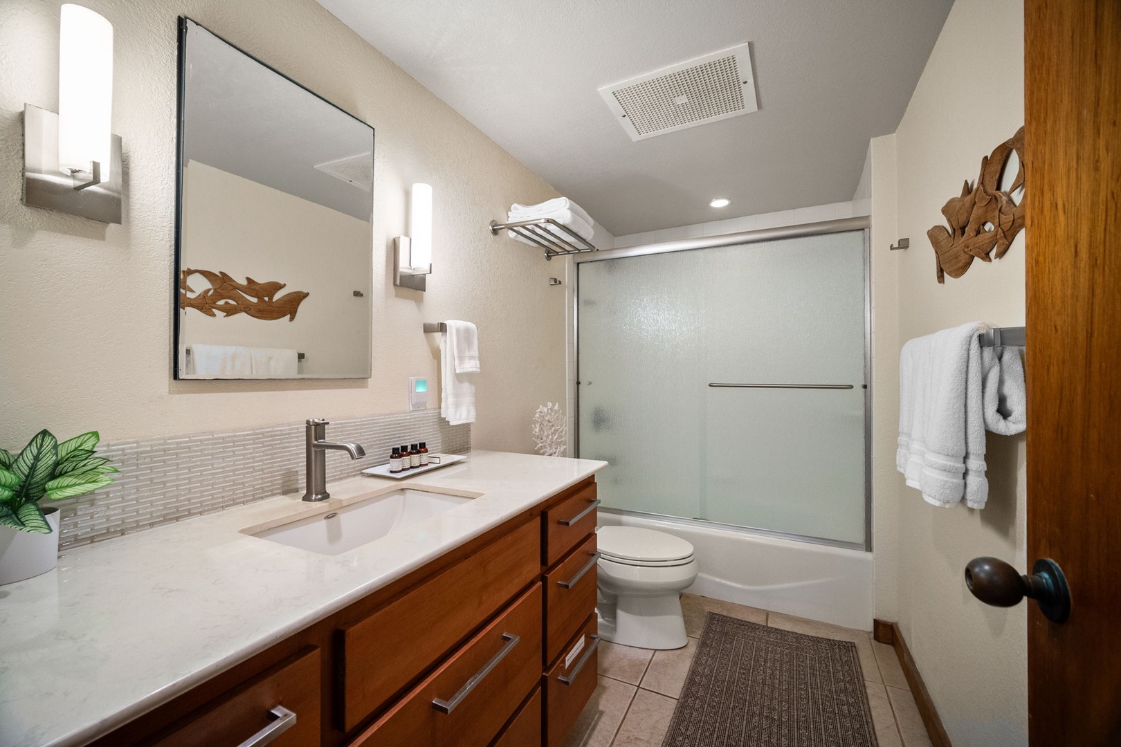 Refresh in your private bathroom featuring a sleek glass-enclosed tub, elegant wood cabinetry, and soft ambient lighting that creates a serene spa-like atmosphere for your daily rituals.