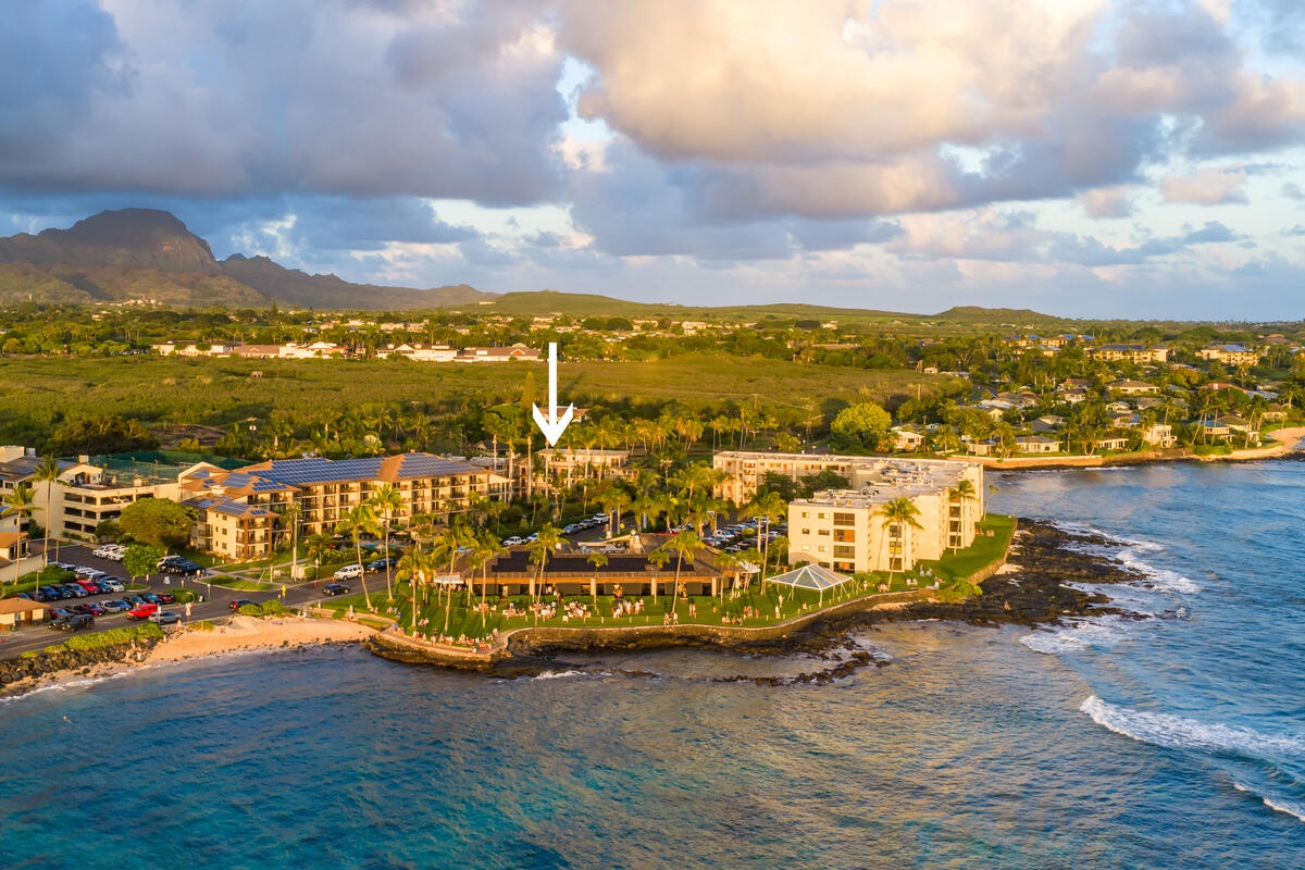 Oceanfront resort complex sits along pristine coastline with mountains beyond, featuring multiple buildings and tropical surroundings in this stunning aerial perspective.