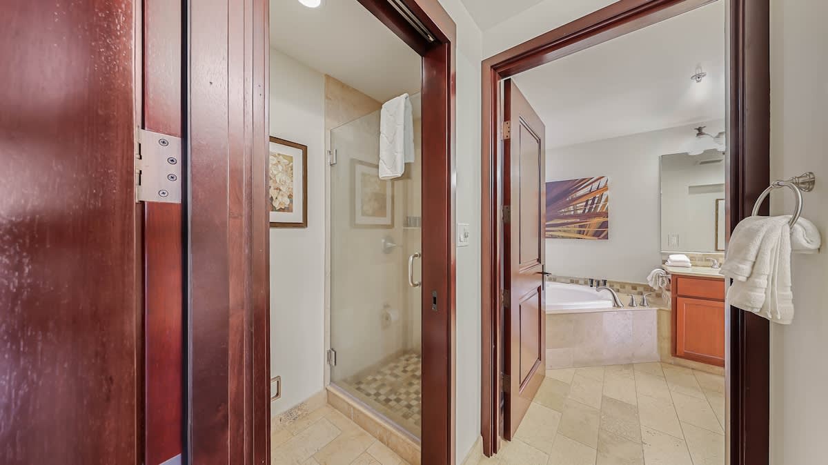 You'll find fresh towels ready in the bright, well-appointed bathroom featuring rich wood accents, a glass shower, and a soaking tub for ultimate relaxation after your adventures.