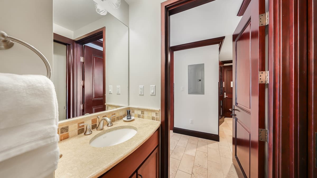 Step into your private bathroom with elegant marble countertops, rich wood cabinetry, and plush towels ready for your stay.