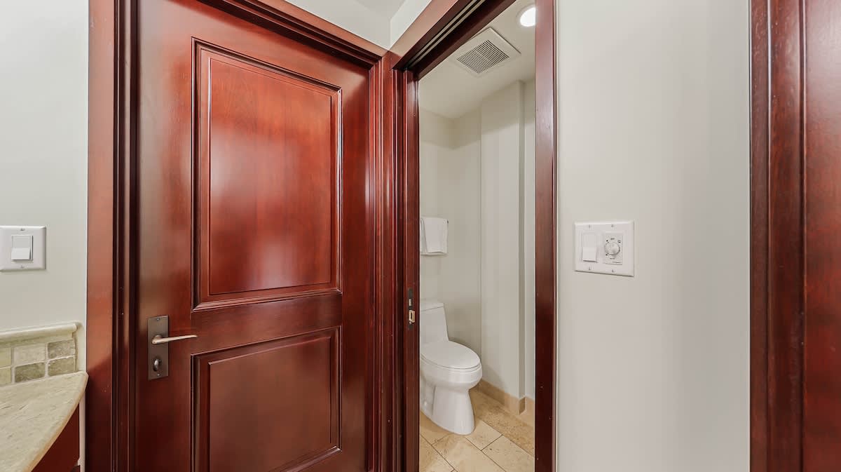 Step into your private en-suite bathroom featuring elegant wood-framed entry and modern amenities—your personal retreat awaits just steps from your bedroom.