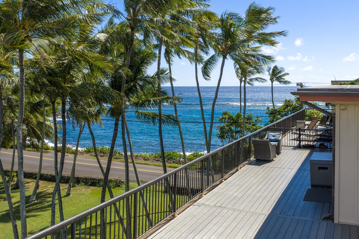 Ocean view property with palm trees swaying in tropical breeze above pristine blue waters and coastal road.