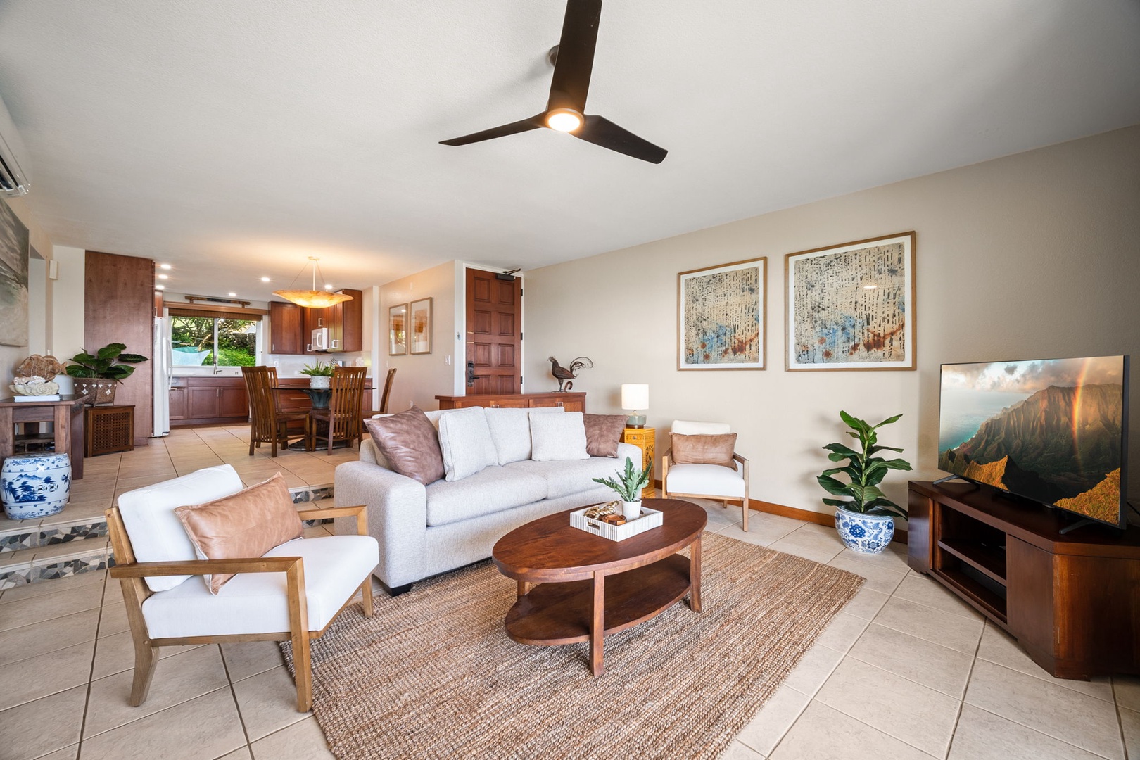 Step into your bright, open living space where natural wood tones and coastal accents create a soothing retreat. Relax on the plush sofa, enjoy the mountain view on your TV, and feel the breeze from the ceiling fan above.