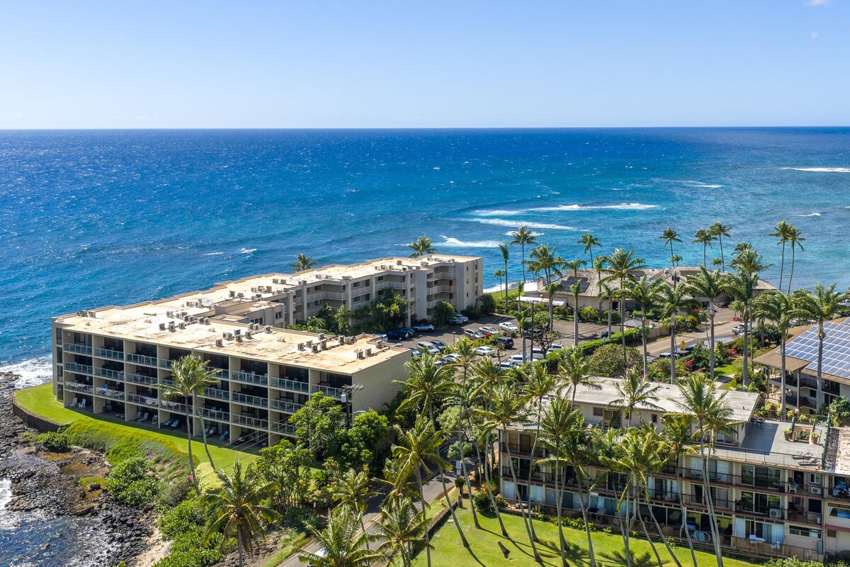 Oceanfront resort complex features modern buildings surrounded by swaying palm trees along pristine coastline with turquoise waters and white sand beaches.