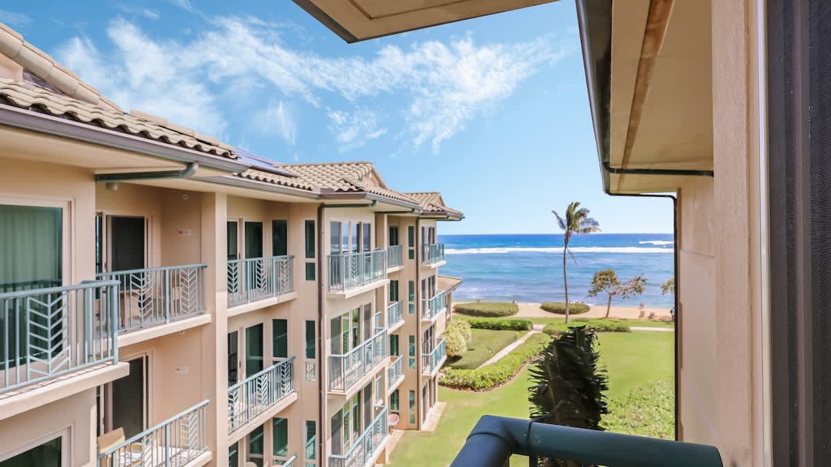 Oceanfront property located steps from the beach, featuring tropical landscaping and views of coastal waters with breaking waves beyond manicured lawns and beachfront areas.