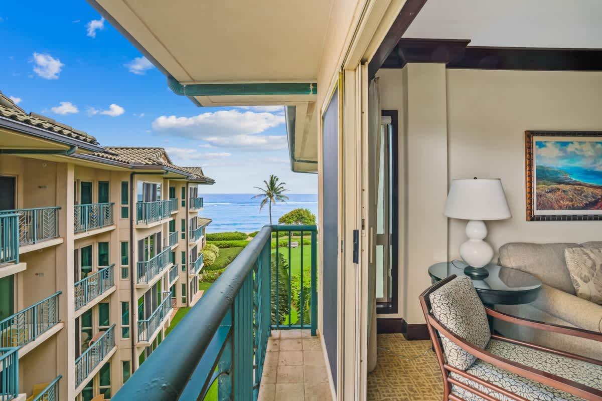 The property features ocean views with tropical landscaping, adjacent buildings, and convenient balcony access from interior living spaces.