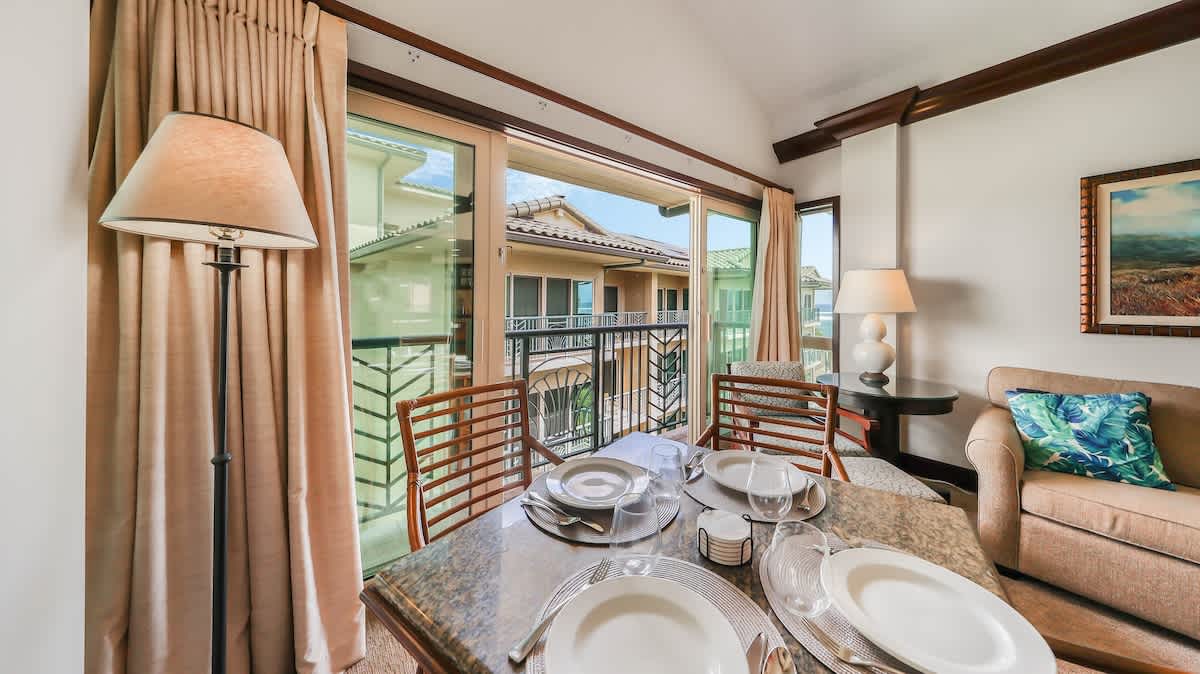 Gather around this inviting dining table set for memorable meals, with balcony doors opening to fresh air and views that make every breakfast or dinner feel special.